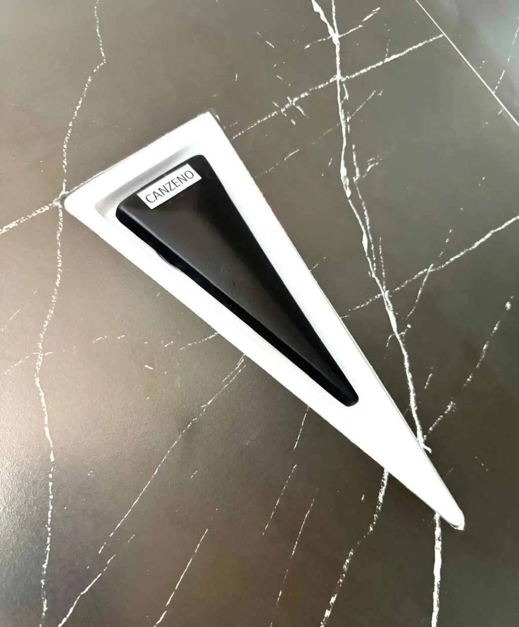 Canzeno Vector Drain, a triangular drain, in a black marble-look tiled shower base