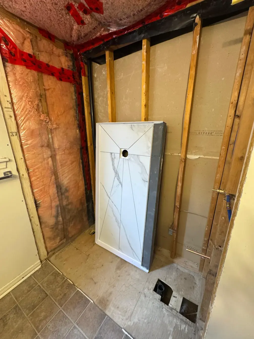 A prefabricated Canzeno tiled shower base standing in a bathroom stripped to the studs, ready to install