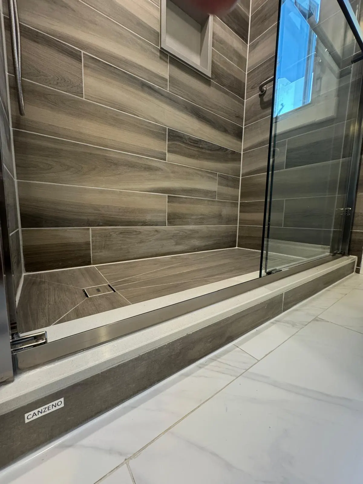 Installed Canzeno tiled shower base with a linear drain and the CANZENO label on its edge