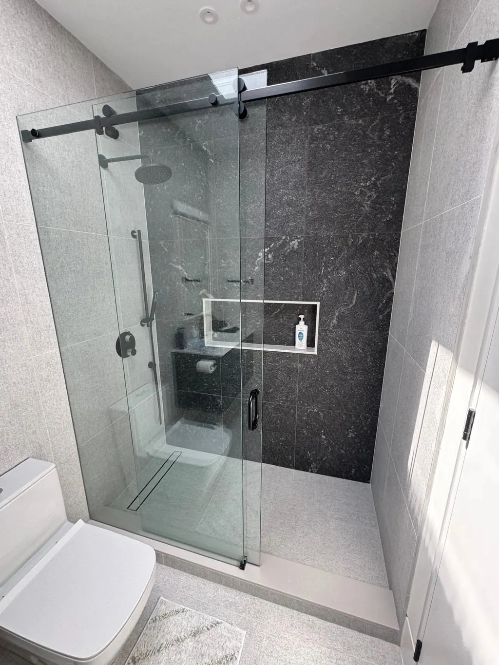 Walk-in shower with a black feature wall, long niche and frameless glass