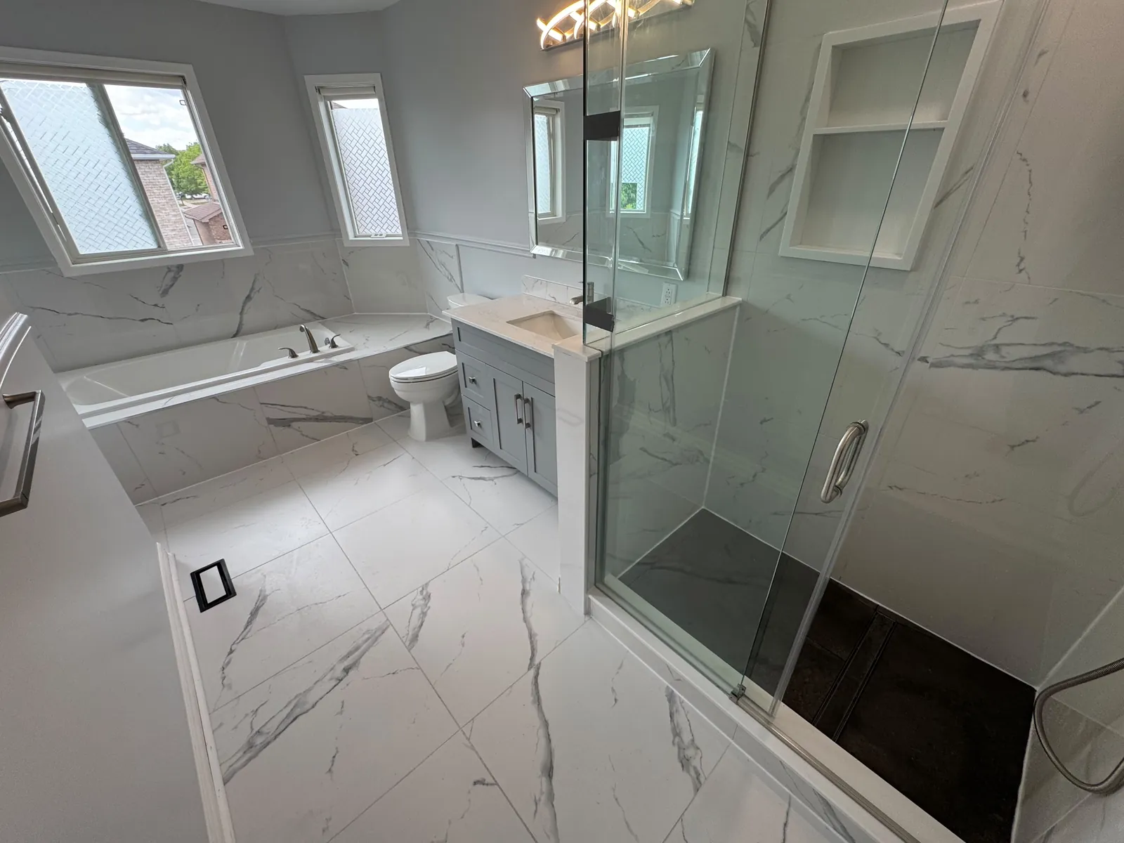 Full bathroom renovation in Aurora by Canzeno, glass shower and marble-look floor